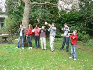 Groep kinderen met zelfgemaakte instrumenten bij een boom